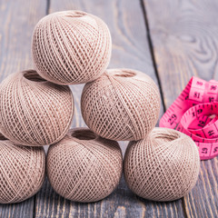 Thread yarns measuring tape on a wooden background
