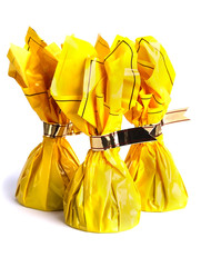 Three chocolates in a yellow wrapping with silver ribbons