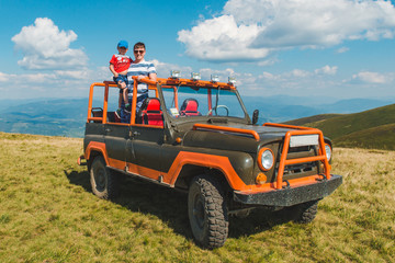 father with son on suv car on the top of the mountain