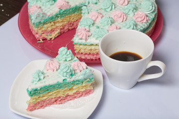 The piece is cut off and lies side by side on a saucer. Nearby is a cup of coffee. Waffle cake made from cream soaked cakes. Decorated with cream flowers.