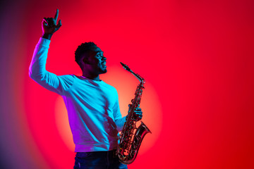 African American handsome jazz musician interacts with audience and holding the saxophone in the...