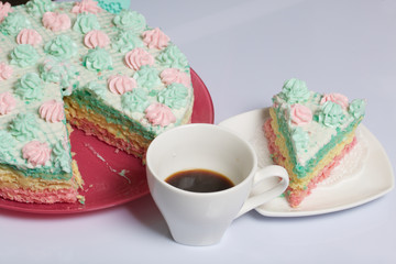 The piece is cut off and lies side by side on a saucer. Nearby is a cup of coffee. Waffle cake made from cream soaked cakes. Decorated with cream flowers.