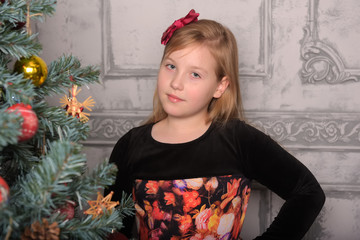 girl blonde child in black with red dress in christmas by the christmas tree