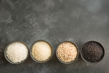 Different varieties of rice. Black rice in bowl on black. Top view.