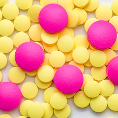 Yellow and pink pills on a white background.