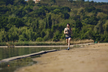 A male runner runs along the road to the park.