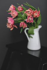 A bouquet of pink peony tulips in a white jug.