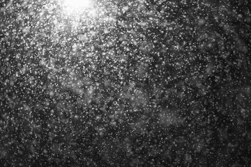 A street lamp illuminates large snow flakes in the evening. Unexpected spring snowfall