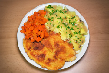 Chicken schnitzel, homemade potatos with chives and carrots, classic polish dinner on wooden background