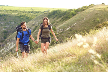 A couple of travelers with backpacks go on a road.