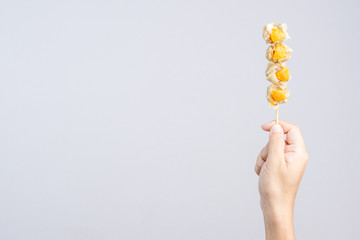 Hand holding pork dumpling stick with salty yolk egg