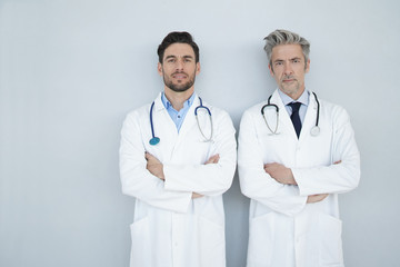 Two doctors looking at camera on grey background