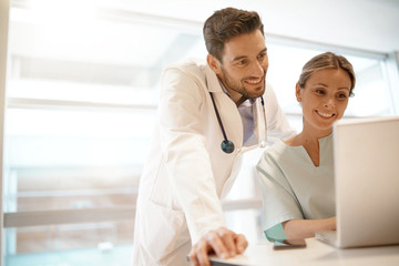 Doctor and nurse going over medical schedule in hospital office