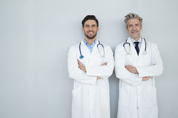 Two doctors looking at camera on grey background