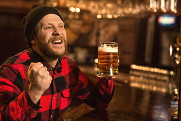 Young bearded man watching football game at the bar