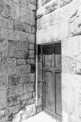 Fototapeta na wymiar this is a black and white capture of an old door located in a monastery and you can see the old architecture of the door surrounded by some beautiful stones 