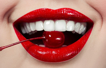 Red lips close-up with bright red cherries at the mouth. beautiful white teeth.