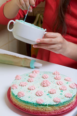 A woman puts a cream in a pastry bag. Round wafer cakes of different colors. For making waffle cake. Nearby there is a can of condensed milk to soak the cakes.
