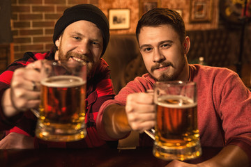 Happy male friends enjoying beer together at the bar