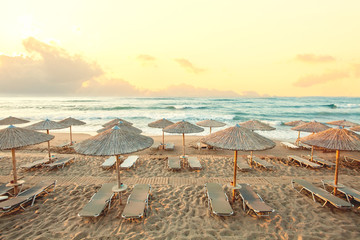 Morning beach, umbrellas, sunbeds and dawn sky. Summer holiday concept