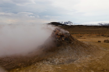 Fumarole in Iceland's Hverir Park, with snowy mountain and cloudy sky in the background