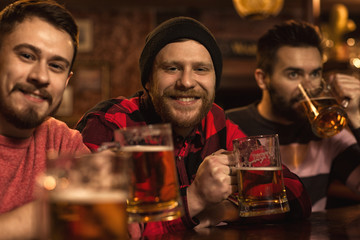 Happy male friends enjoying beer together at the bar