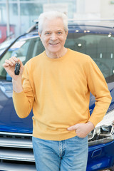 Cheerful elderly man showing car keys to his new auto