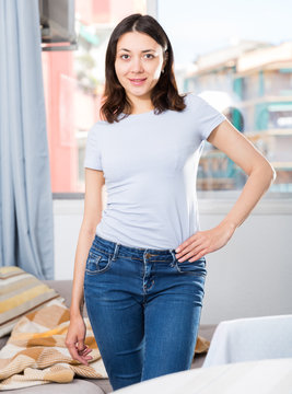 Girl dressed blue jeans standing at room in home interior