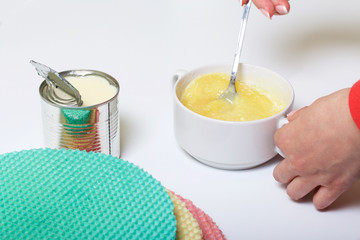 Round wafer cakes of different colors. For making waffle cake. The woman mixes the impregnation for the cake layers. Nearby there is a can of condensed milk to soak the cakes.