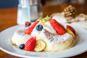 Fruit Salad Souffle Pancake with fresh strawberry, berry, banana, whipped cream and maple syrup