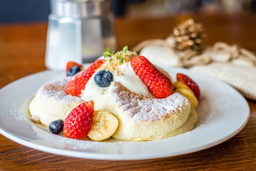 Fruit Salad Souffle Pancake with fresh strawberry, berry, banana, whipped cream and maple syrup