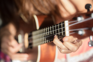 Women playing ukulele music with light of sun