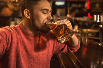 Cheerful handsome young man taking a selfie while drinking beer at the bar
