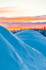 Arctic sunrise peeks over wind sculptured snow mounds in Kirkenes, Norway