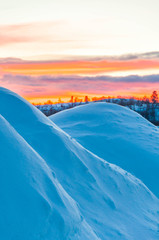 Arctic sunrise peeks over wind sculptured snow mounds in Kirkenes, Norway