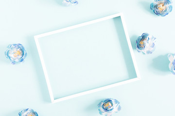 Flowers composition creative. Blank photo frame, light blue flowers on pastel blue background. Flat lay, top view, copy space