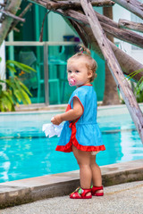 Naklejka premium a girl in a blue dress with a white bow is surprised, rejoices, screams, cries, raises her hands. children's fashion concept.