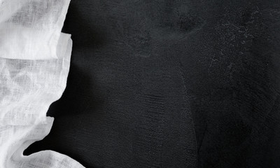 White linen tablecloth on black stone table background. Flat lay, top view, copy space