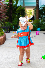 a girl in a blue dress with a white bow is surprised, rejoices, screams, cries, raises her hands. children's fashion concept.
