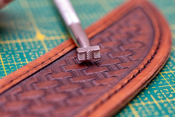 Fototapeta na wymiar Creating stamping pattern on the leather sheath, working with leather, leathercraft