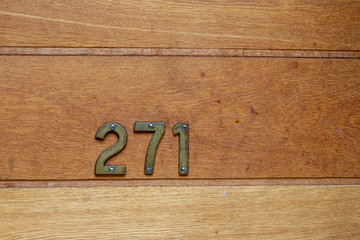 The number 271 on a natural wooden house door with the two hundred seventy one as bronze numbers 