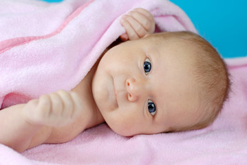 Baby girl lying on a pink blanket