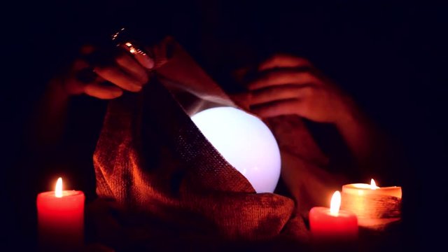 Fortune teller is reading the future with a crystall ball on his table.