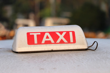 Taxi light sign or cab sign in white and red color with white text on the car roof at the street...