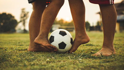 An action sport picture of a group of kids playing soccer football for exercise in community rural area under the sunset.