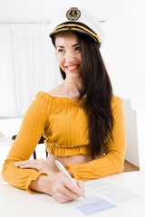 Attractive woman sitting and white table and writing with pena nd smiling.
