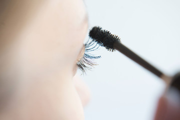 Close up of a young woman applying mascara on a white background. Make-up And Cosmetics Concept. Long Black Thick Eyelashes Applying Mascara With Cosmetic Brush. 