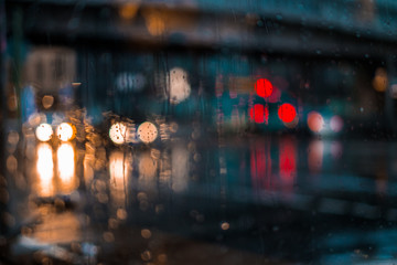 Night city life through windshield: cars, lights and rain.