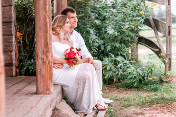 Bride and groom are sitting on the threshold of a wooden house