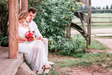 Bride and groom are sitting on the threshold of a wooden house